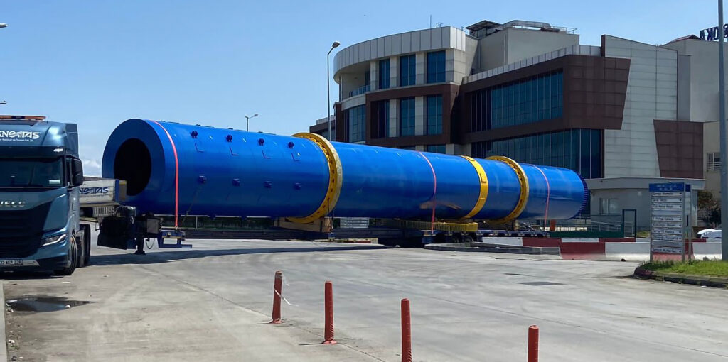 A large blue rotary drum dryer with yellow support rings on a heavy-duty trailer